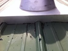 Stove pipe flashing on corrugated metal roof.