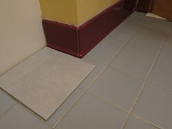 wooden baseboard in a tile-floor bathroom