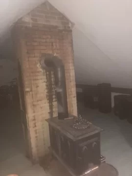 Stove in attic - vent with 90 into brick chimney, OR use Class A pipe straight through metal roof?